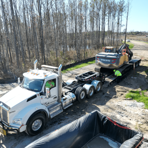 Truck unloading excavator at jobsite