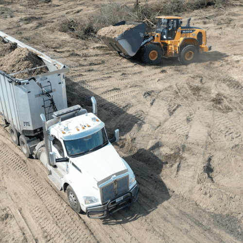 Loader driving to semi truck for land clearing